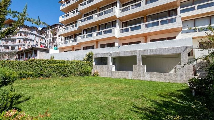 Image of the facade of the hotel with a lush green lawn in the front  | DLS Serenity Resort and Spa